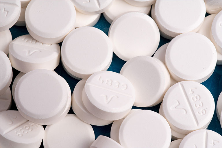 A zoomed in image of a bunch of non-descript, white, circular pills.
