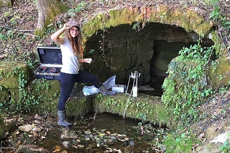 An IU student researcher from the Indiana Geological and Water Survey investigating a mineral spring.